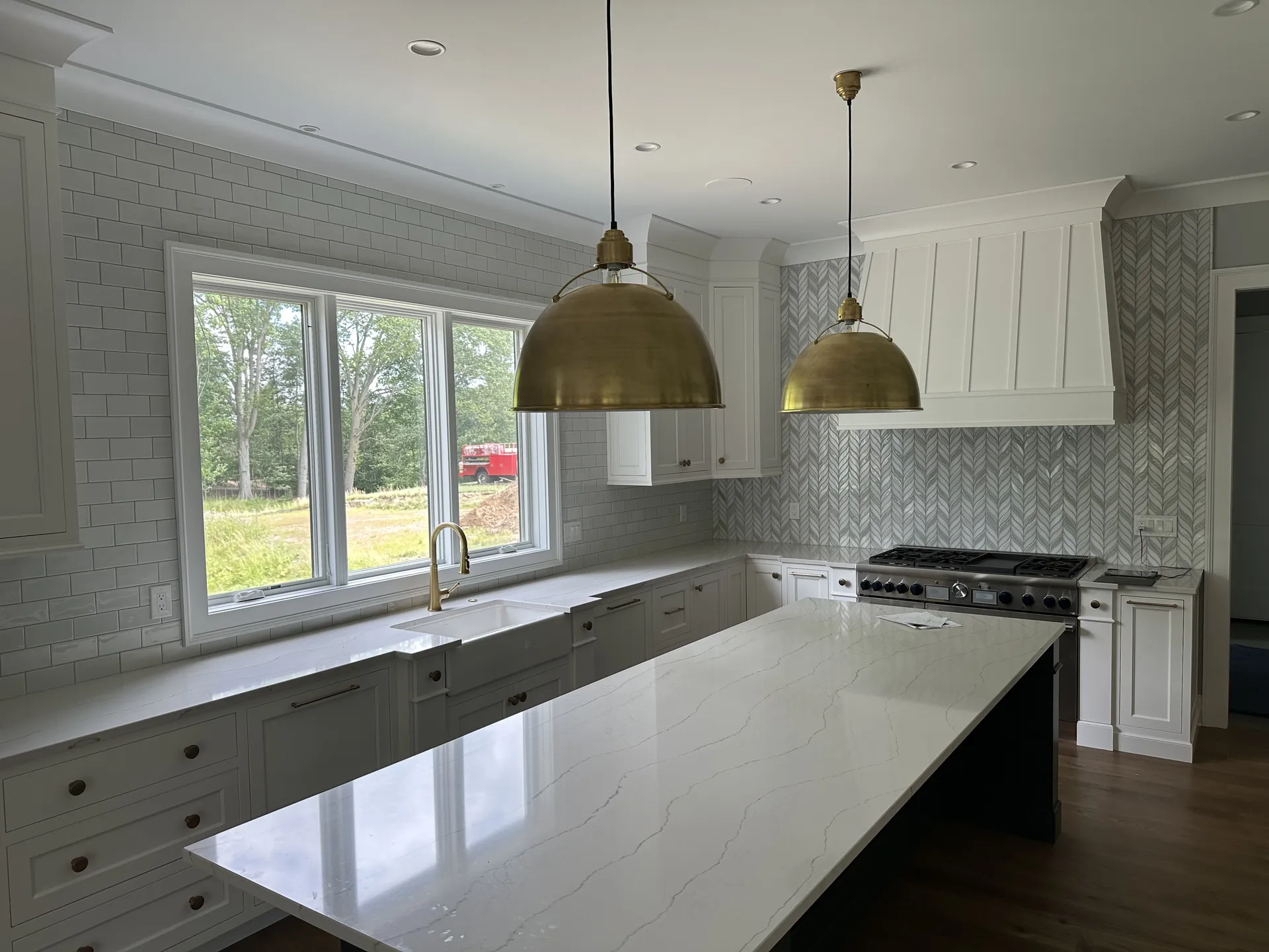 Completed kitchen remodel with white cabinetry, marble-look counters, and custom tile backsplash